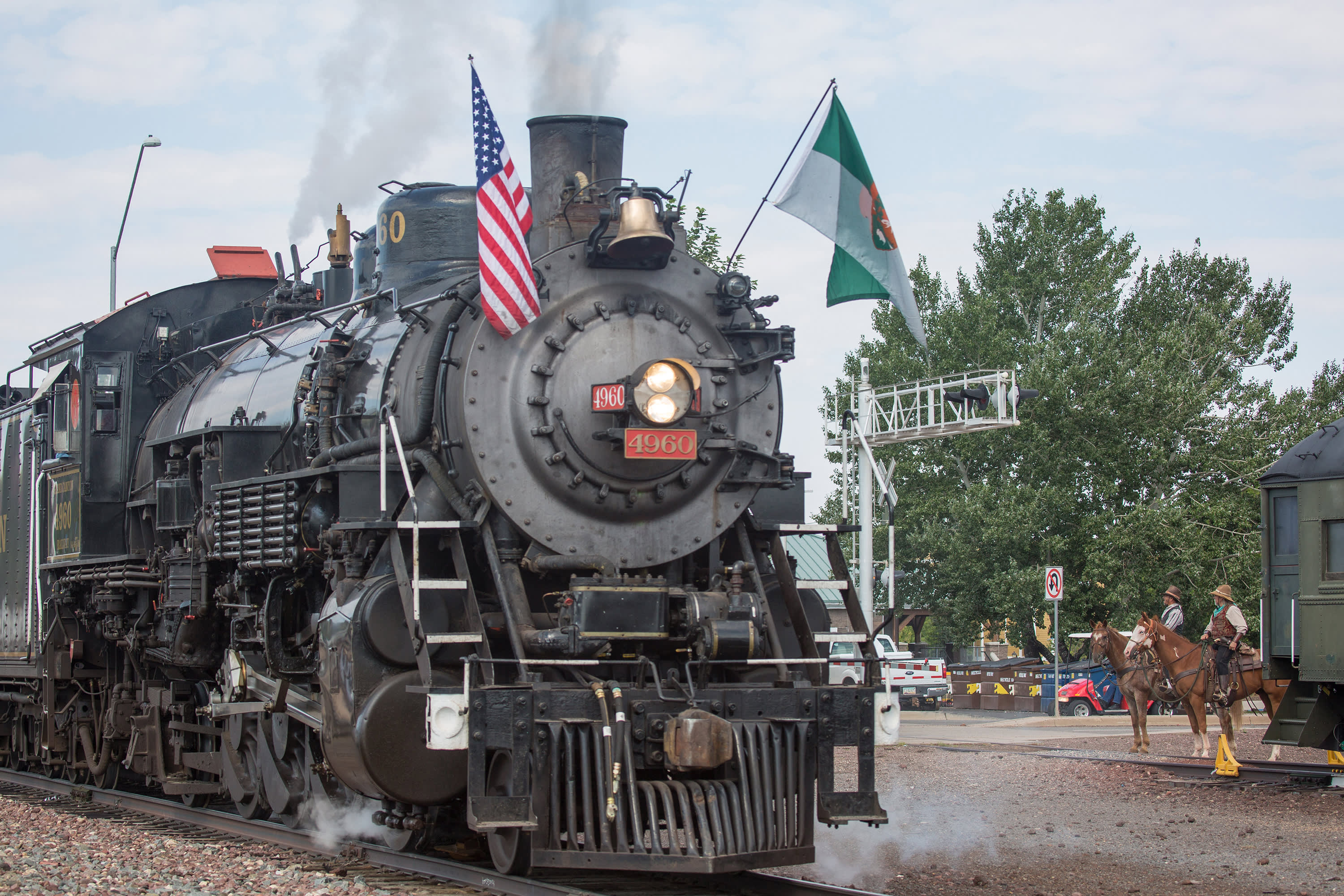 A Grand Canyon Railway Train goes past a rider on a horse.