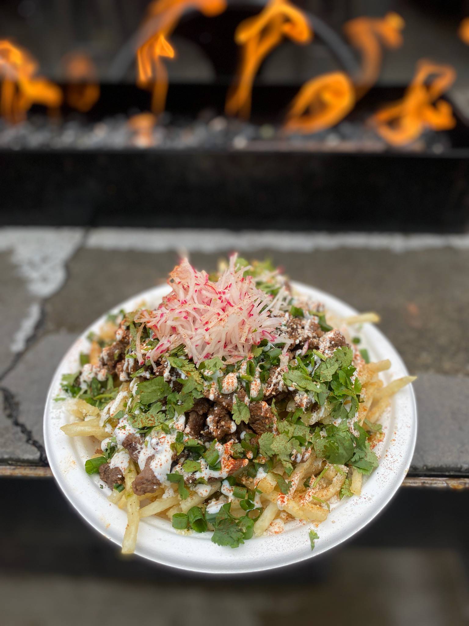 Carne asada fries from Á La Carte in Bend, Oregon on a paper plate.