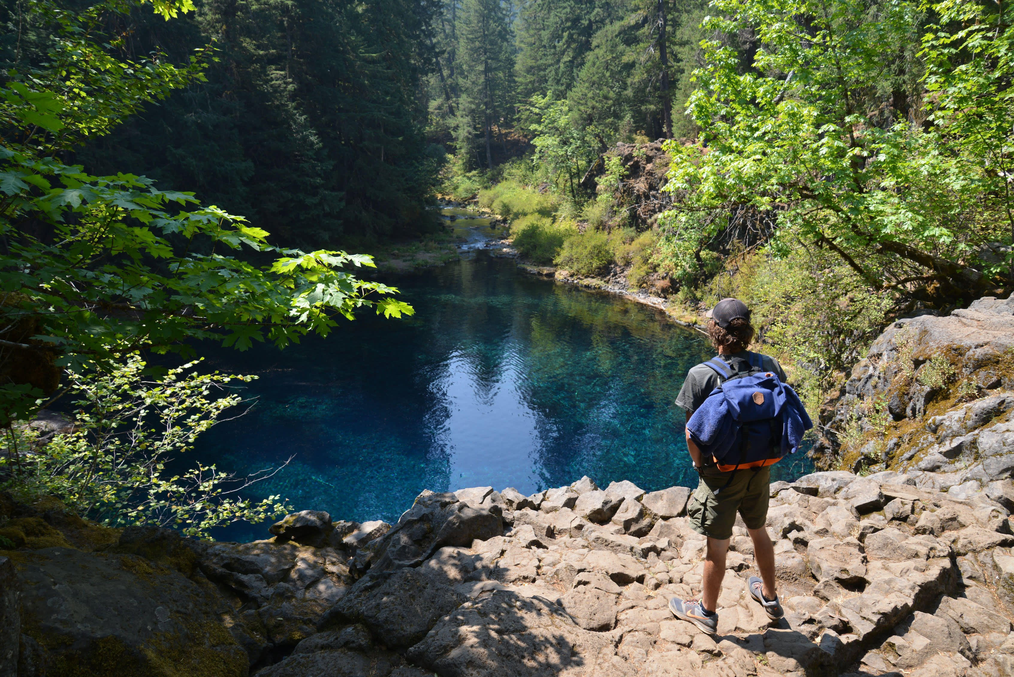 A hiker stands above the otherworldly Blue Pool beneath Tamolitch Falls on the McKenzie River in Oregon.