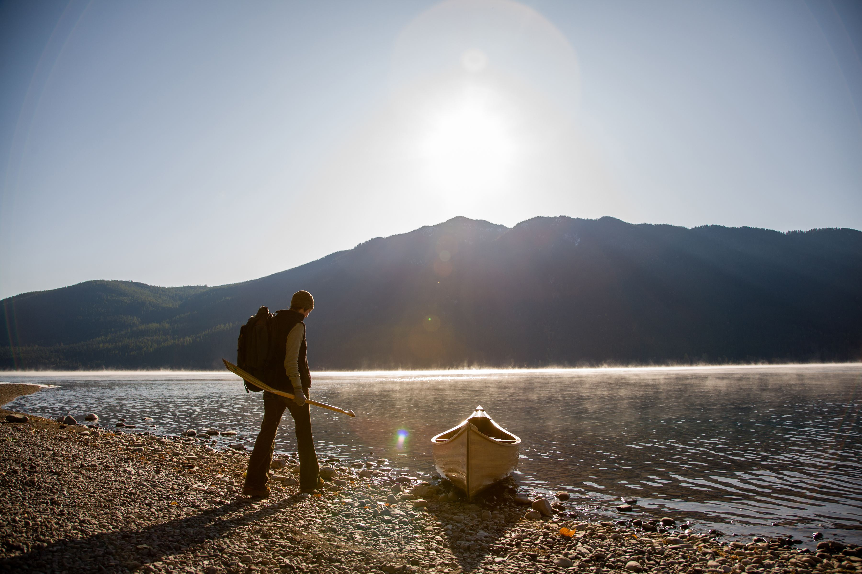 A person readies a canoe on the shore of Lake McDonald in Glacier National Park.