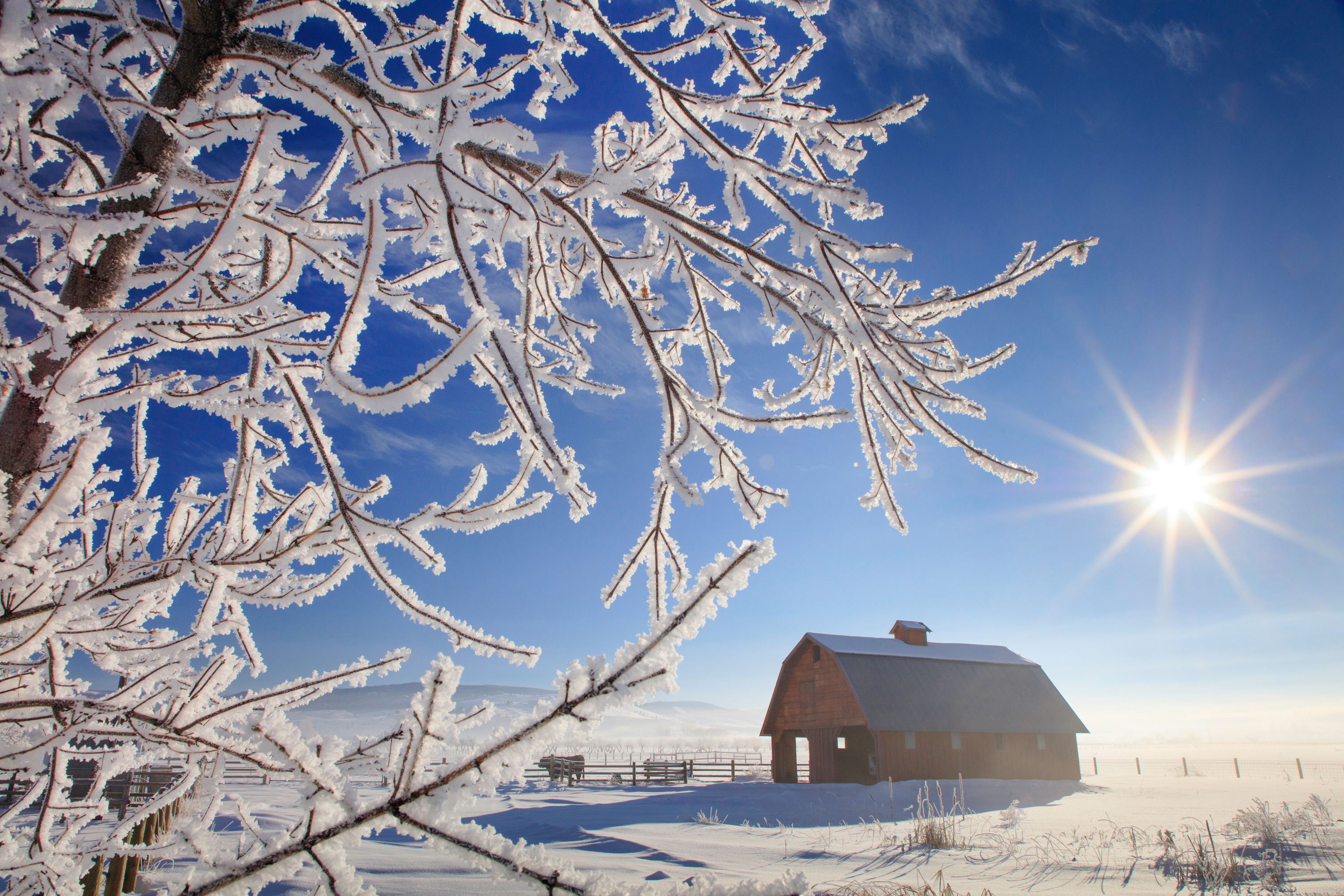 A red barn near Stevensville, Montana dusted in a light layer of snow on a clear winter day.