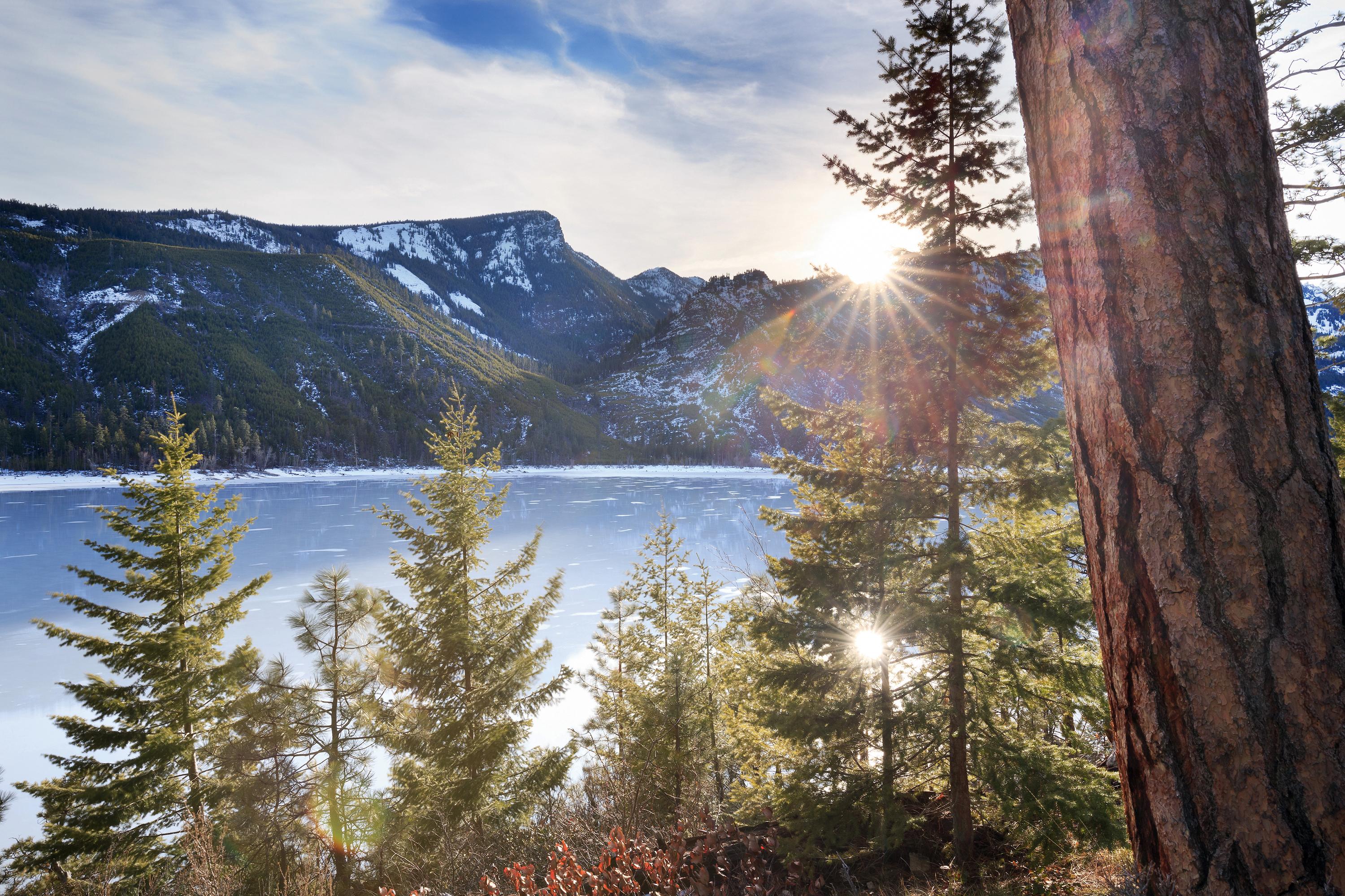 The sun peaks over the mountains that surround Montana's Lake Como in winter.