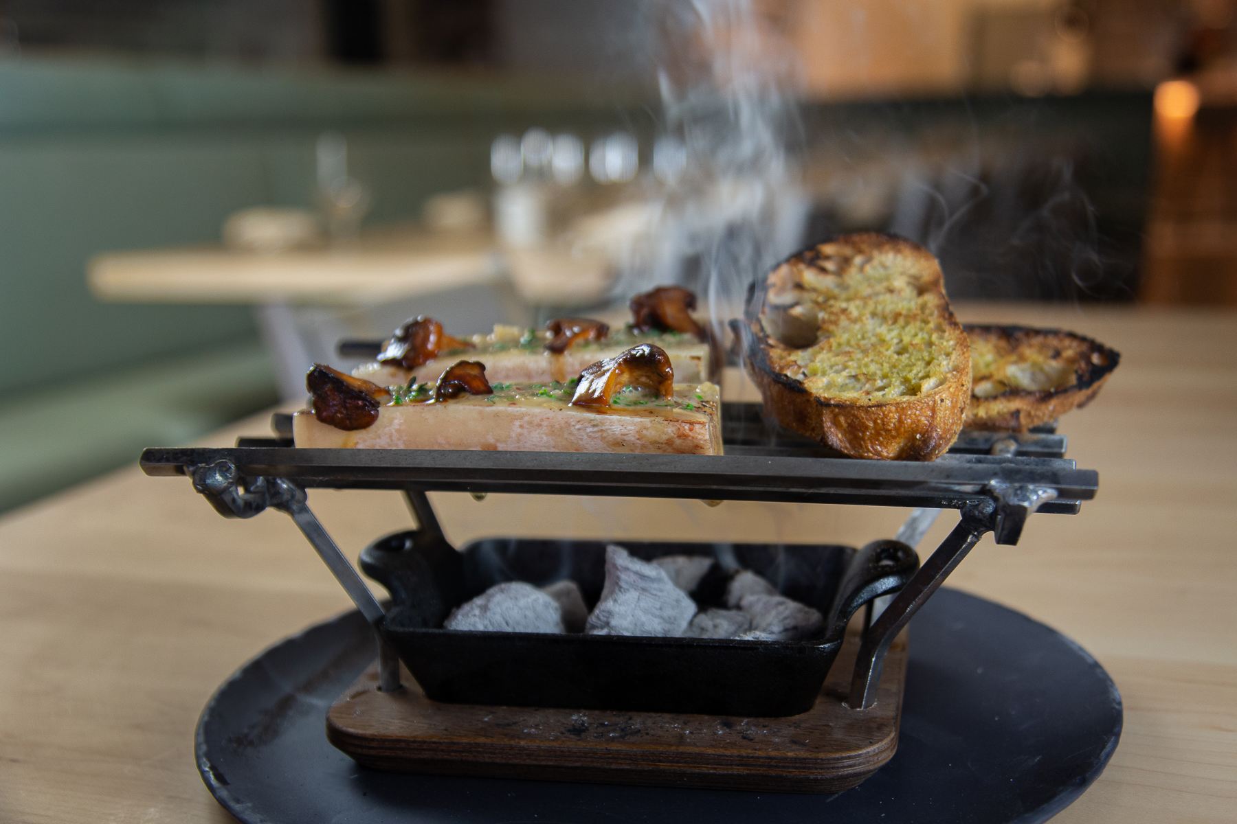 Roasted bone marrow appetizer on flatbread over a charcoal grill at Atria.