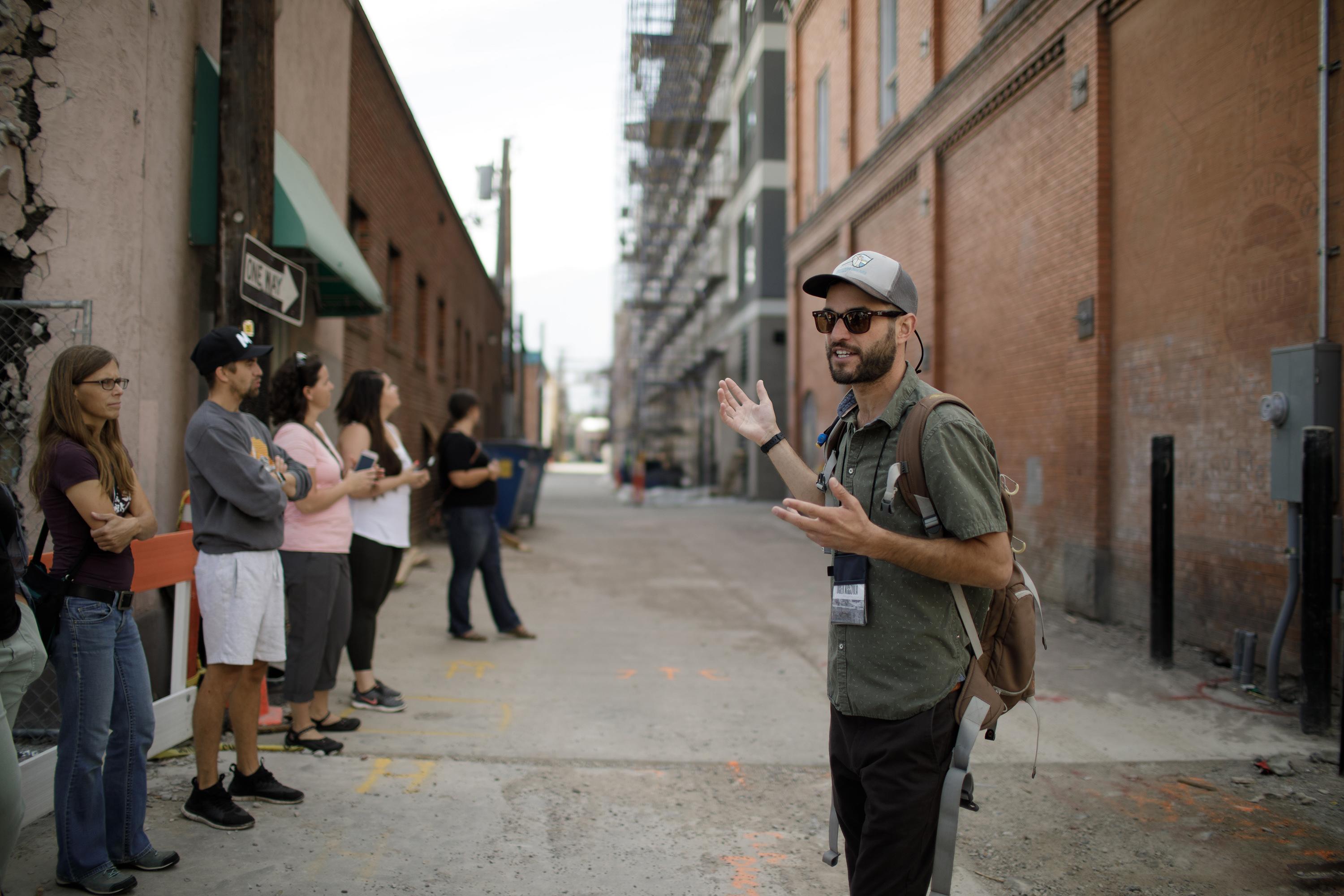 A group listens to a tour guide on the Unseen Missoula's Basements and Back Alleys tour.