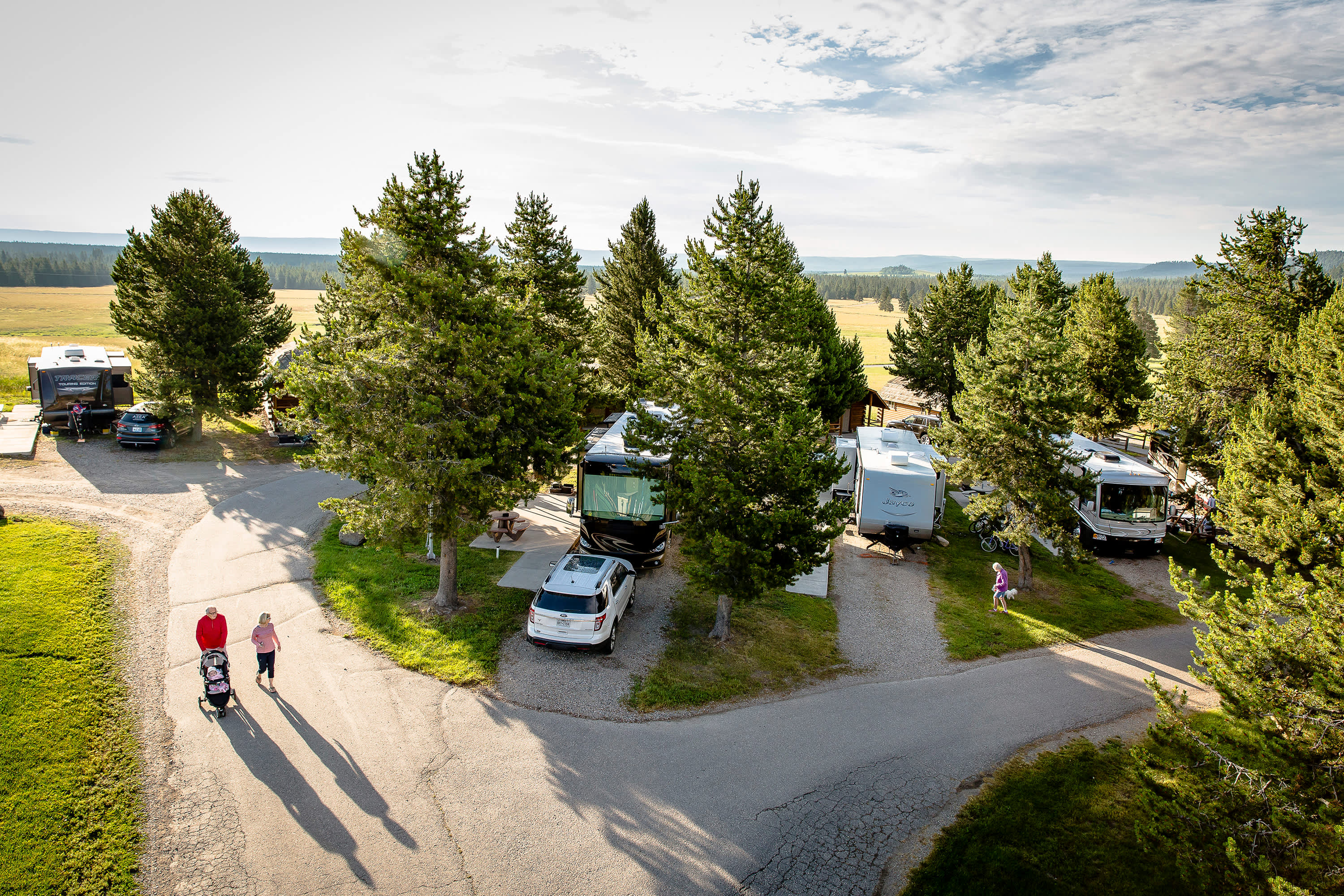 Grandparents push their grandchild in a stroller along the paths of Yellowstone Park/West Gate KOA Holiday in West Yellowstone, Montana