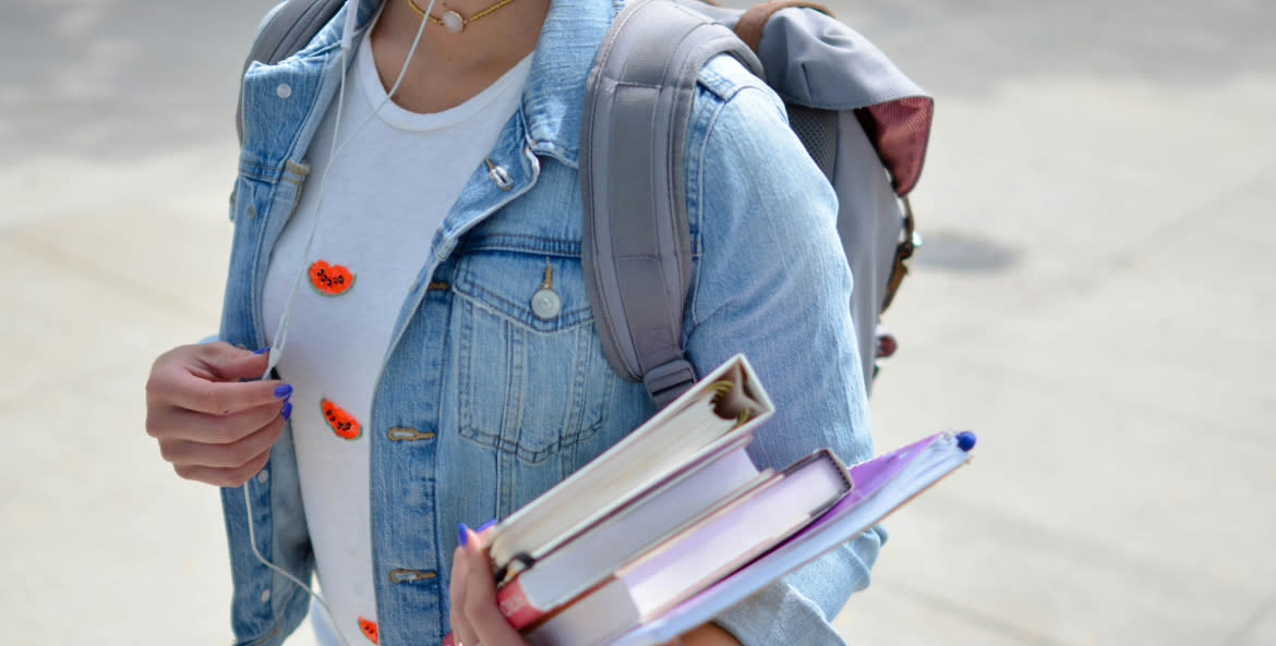 A college student with an armful of books protects themselves from identity theft scams