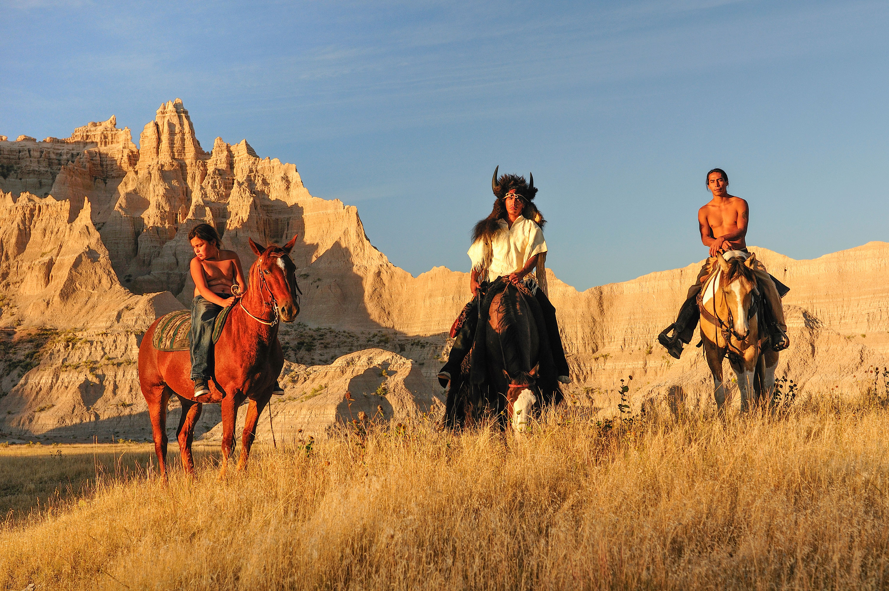 Three Lakota tribal members ride horses through the Pine Ridge Indian Reservation in South Dakota.