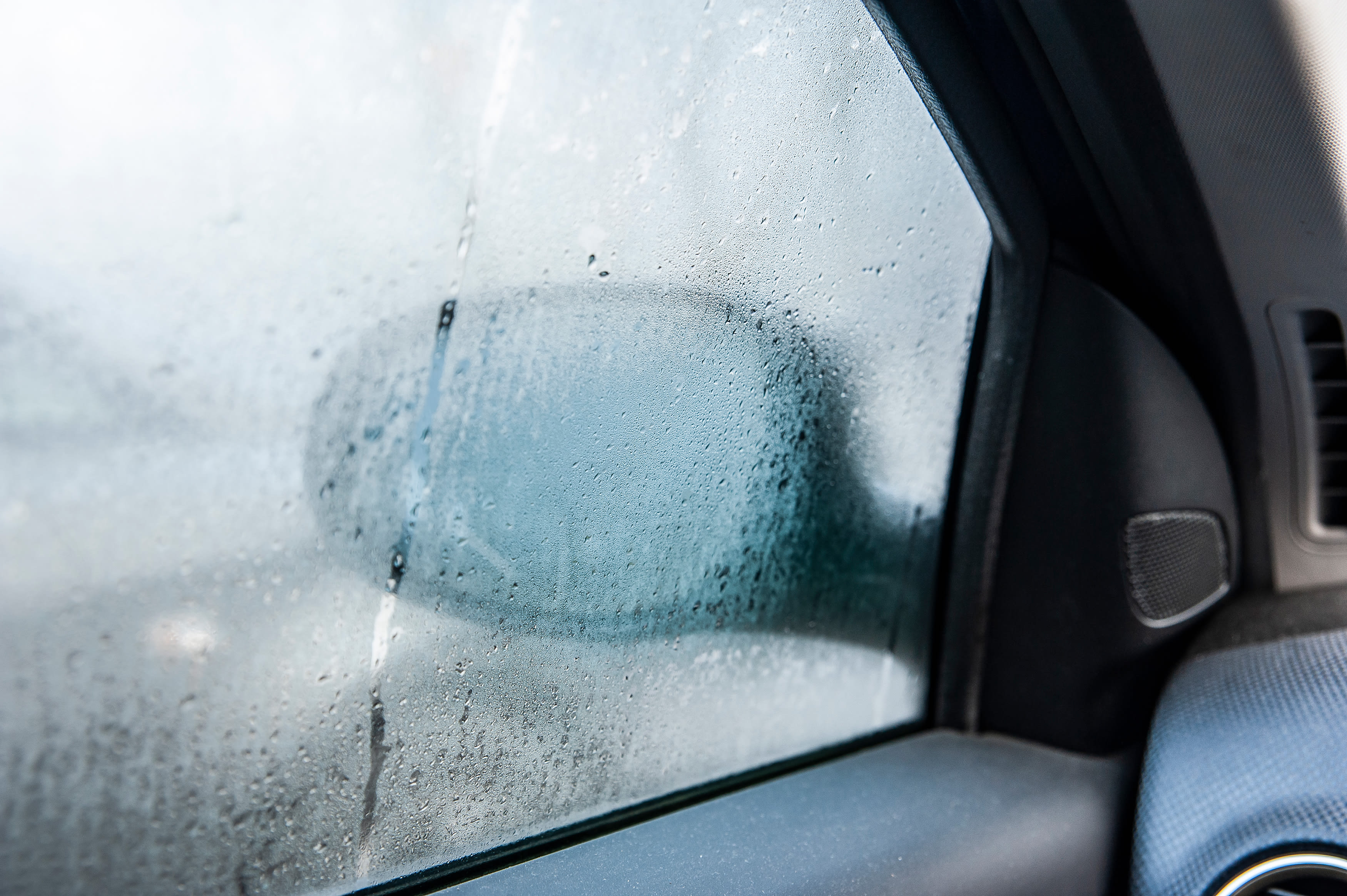 Condensation fogs up a driver-side car window.