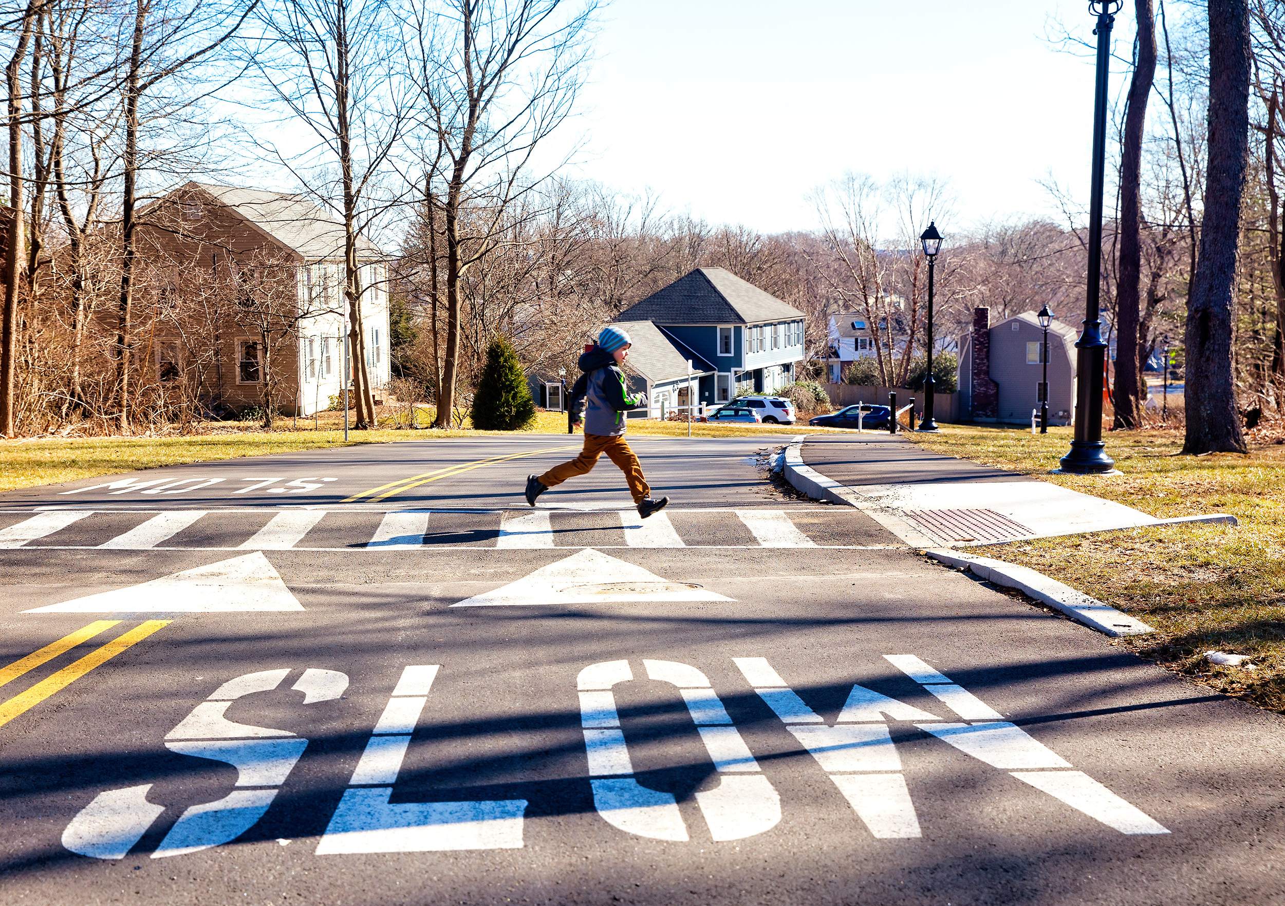 A child runs across a crosswalk in fall.