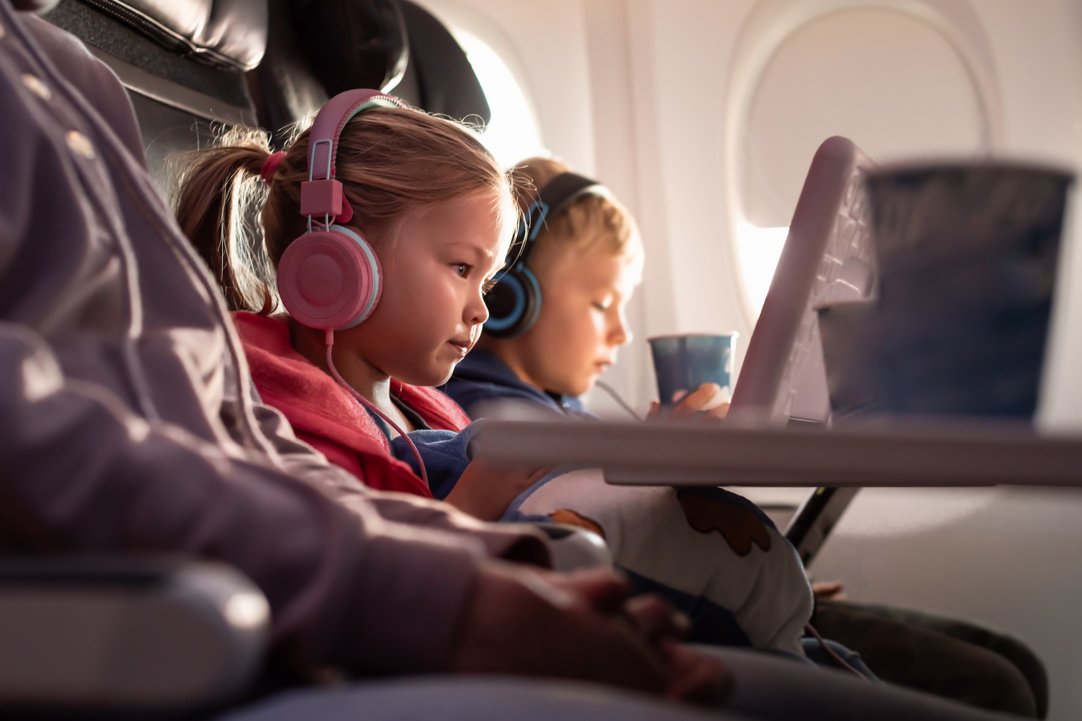 Siblings watch a movie together on a long flight.