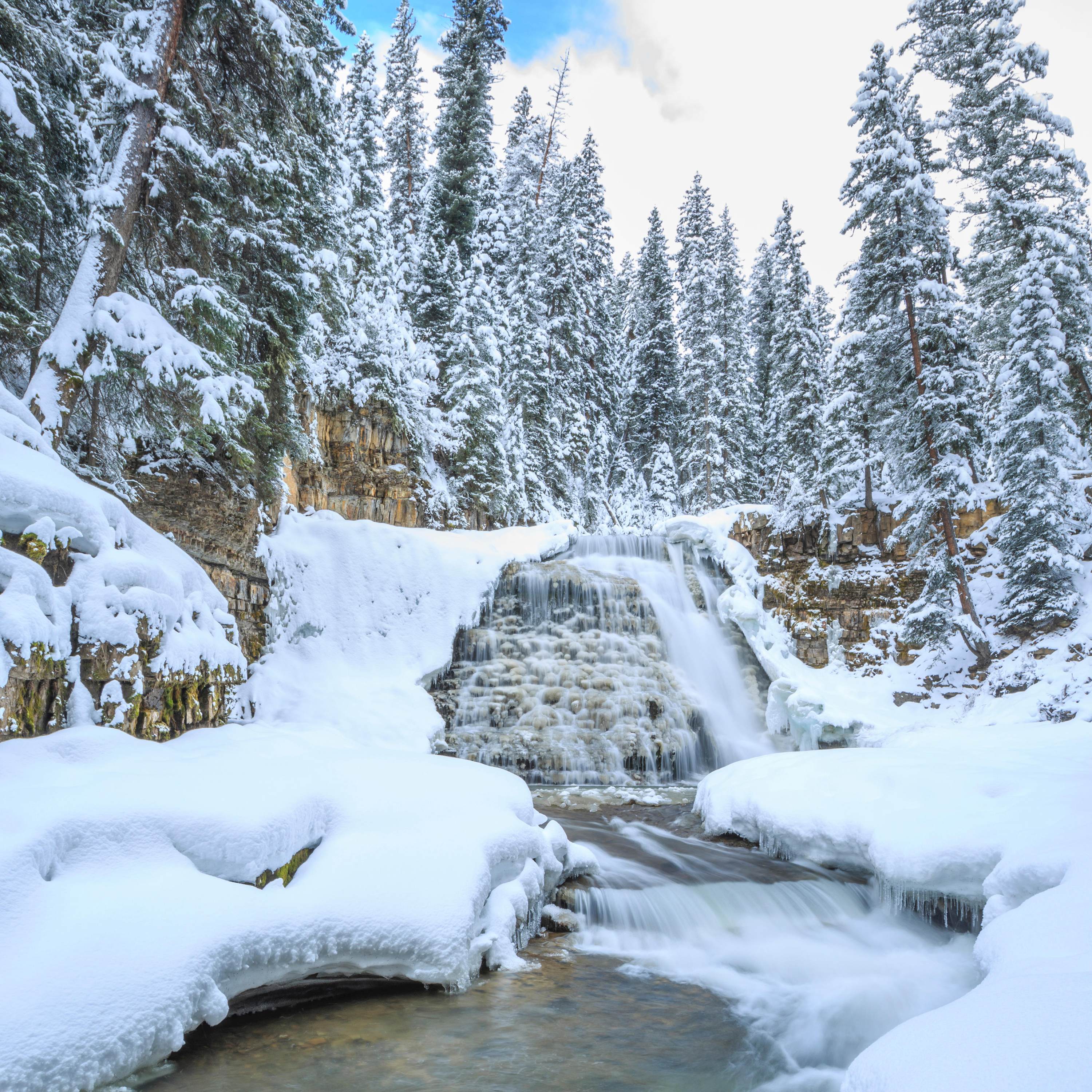 Ousel Falls runs through frozen banks in winter near Big Sky, Montana.