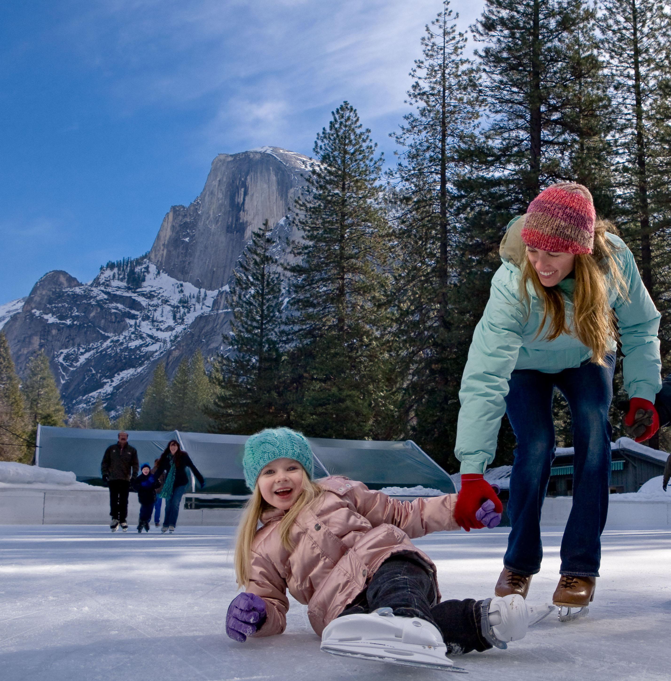 A mom and her daughter ice skate together at Yosemite National Park's Curry Village Ice Rink.