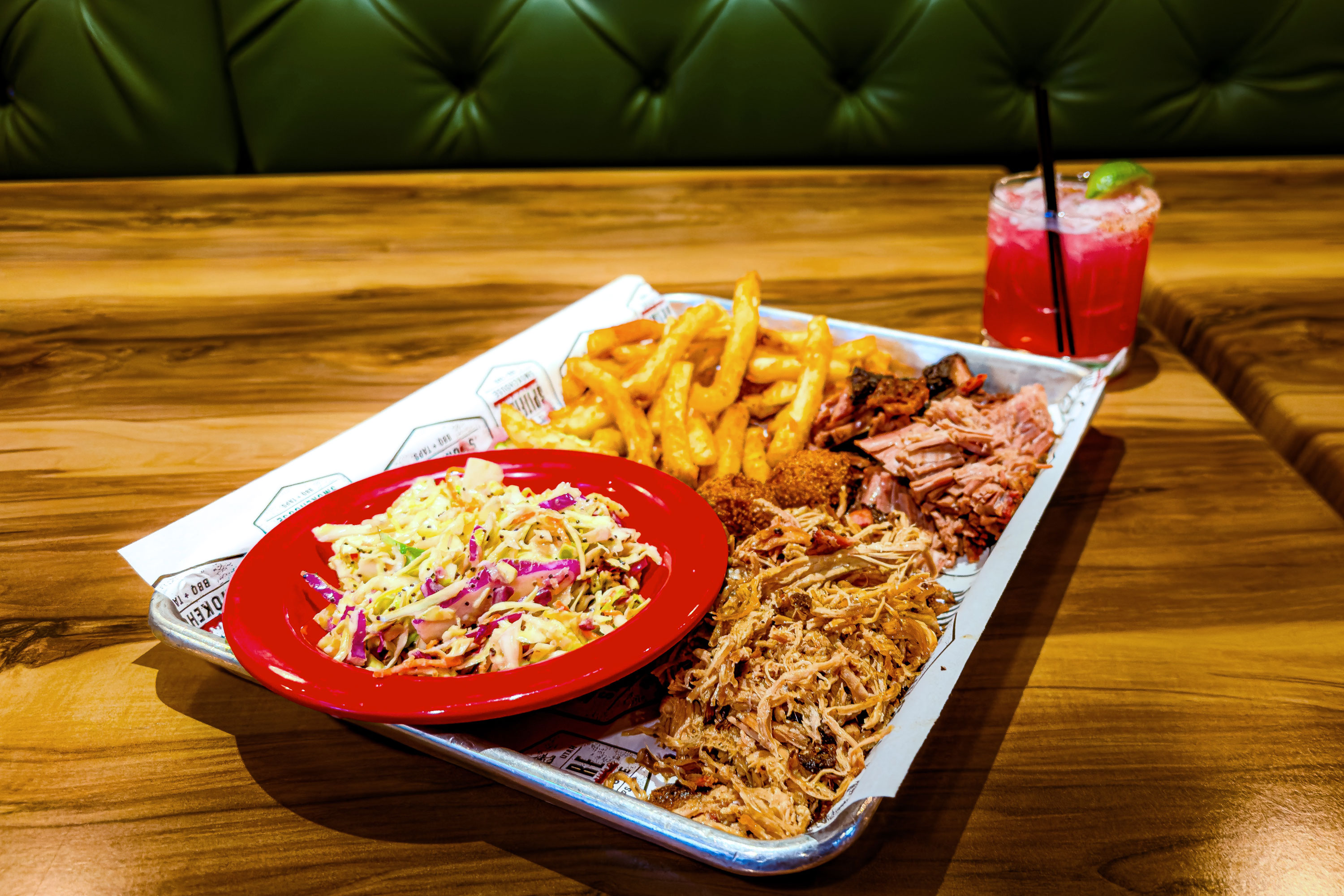 A tray of Texas-style brisket, pulled pork, poppy seed coleslaw, and beer-battered fries on a table at Spitfire Smokehouse + Taps in Moab, Utah. 