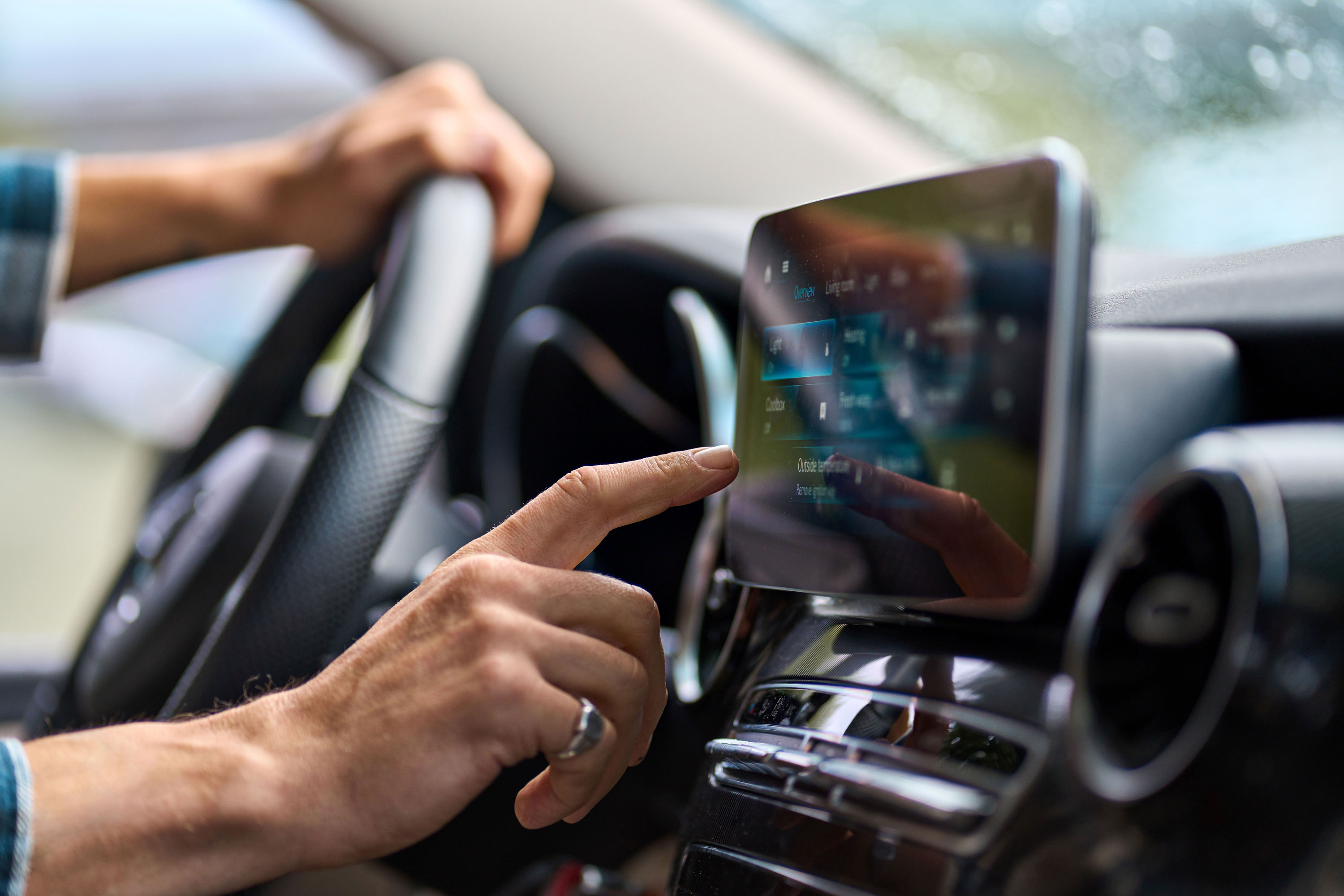 A driver interacts with their vehicle's infotainment screen while driving.