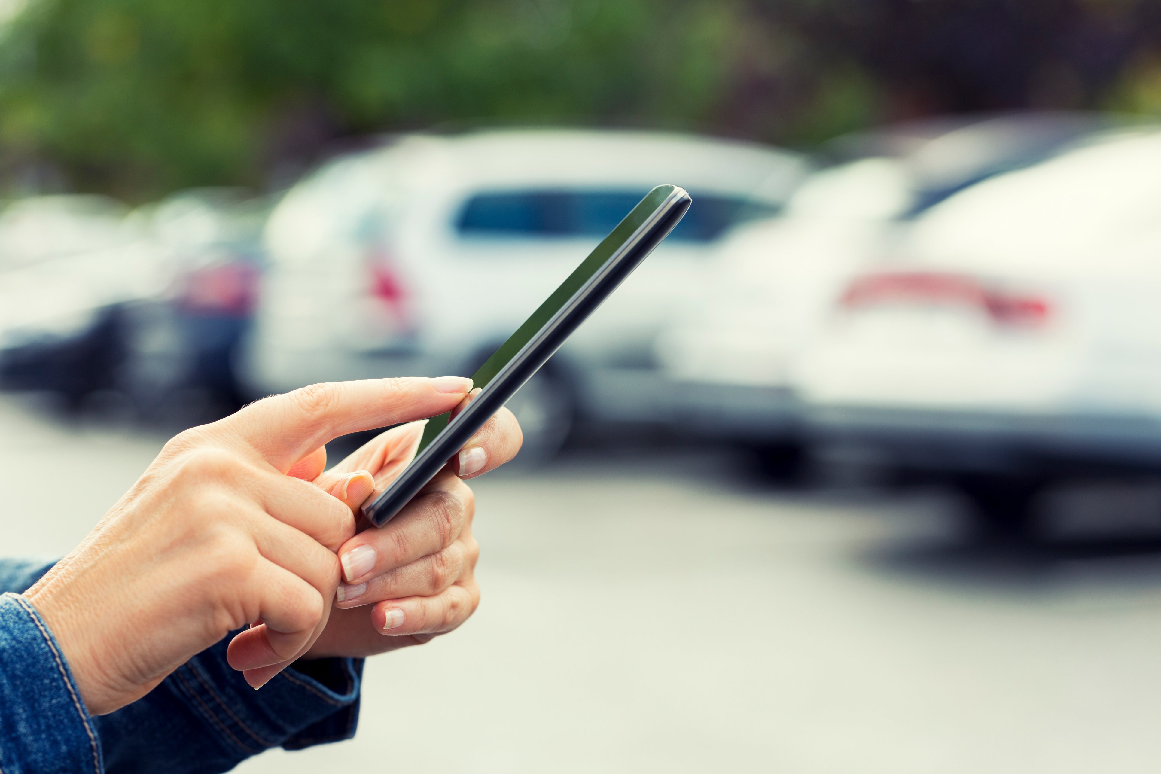 A person calls for roadside assistance after locking their keys in their car in a parking lot.